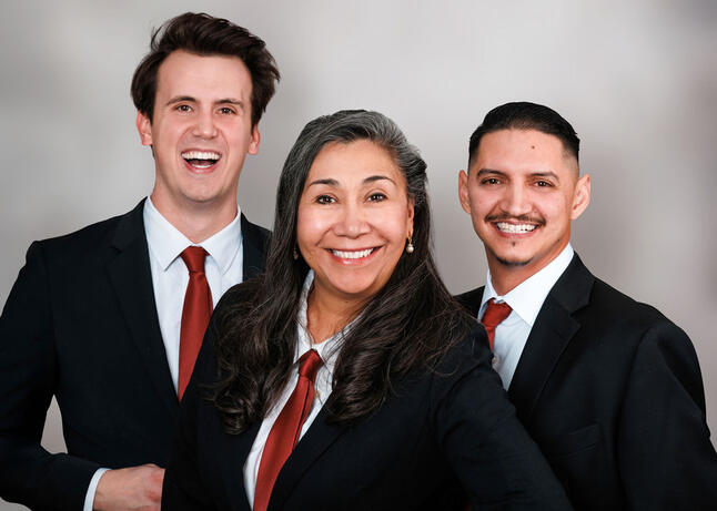 A portrait of a team of 3 Real Estate Agents in black suits with red ties.