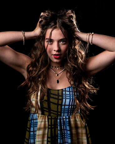 An editorial portrait of a woman with her hands in her hair.