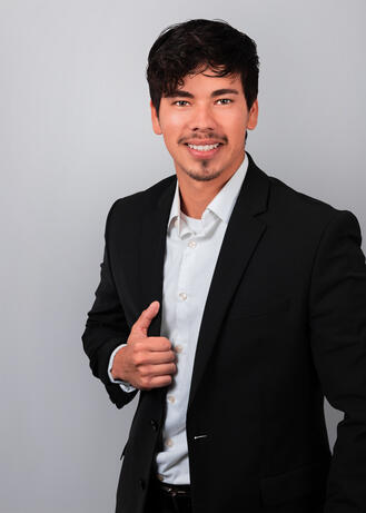 A professional headshot of a man wearing a white shirt and black suit jacket.